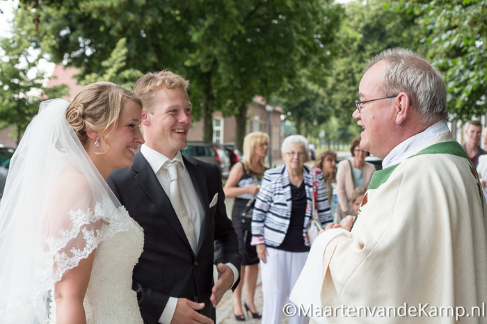 De bruid en bruidegom worden door de pastoor bij de kapel ontvangen